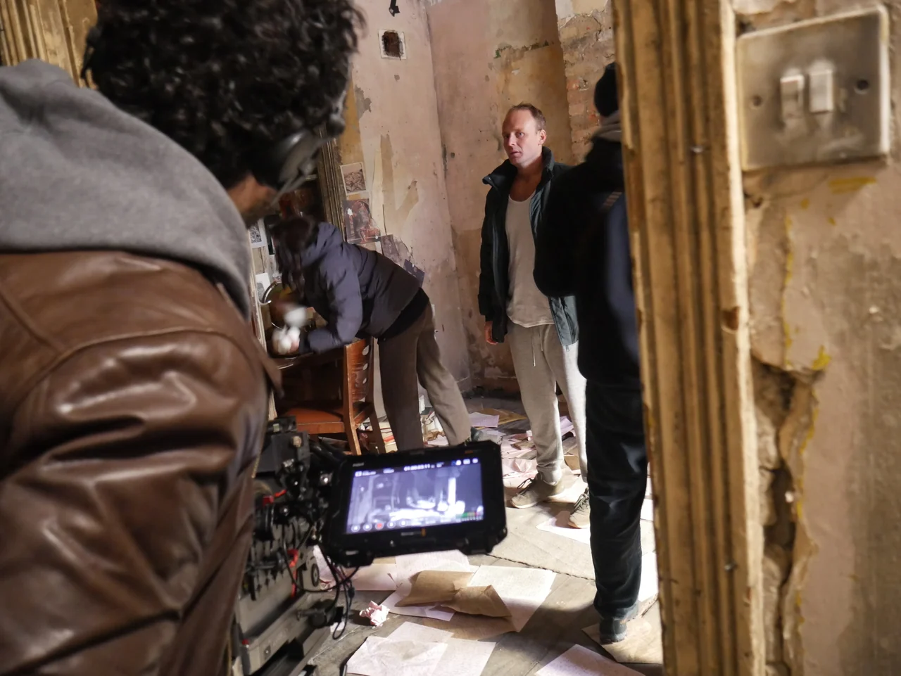 Cast and crew prepare a shot beside the camera monitor on Universe25.