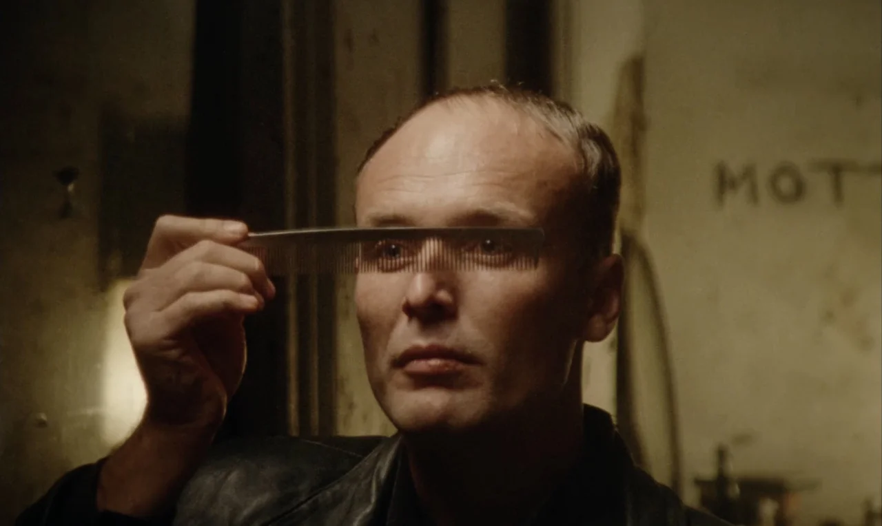 Mott studies his reflection and combs his hair in a dimly lit room.