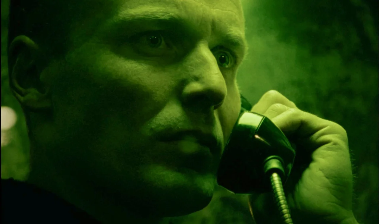 Mott listens to his mysterious caller under an electric green light.